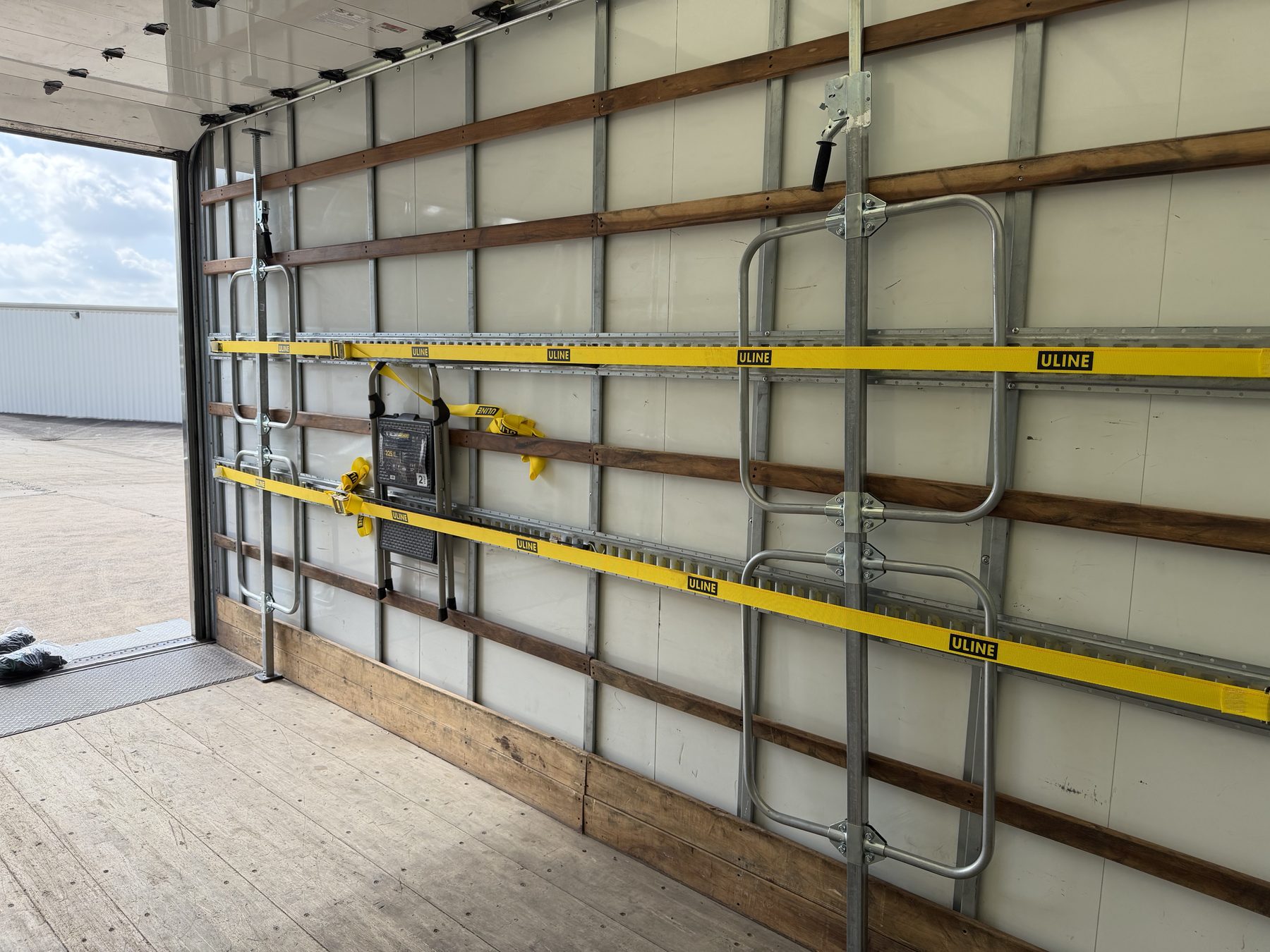 Close view of E-track logistics rails with ratchet straps and load bars mounted